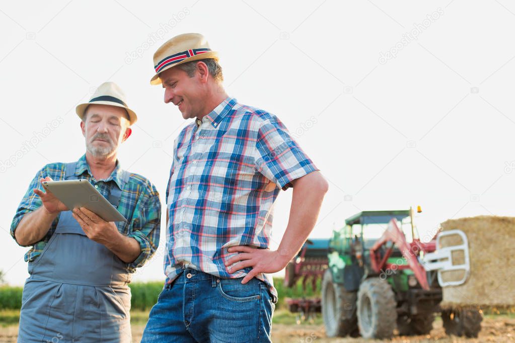 Smiling farmers communicating over digital tablet at farm