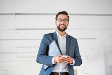 Ofiste akıllı telefon kullanan çekici sakallı iş adamı.