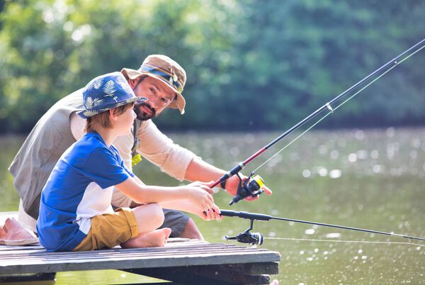 Father and son fishing in Lake while sitting on pier