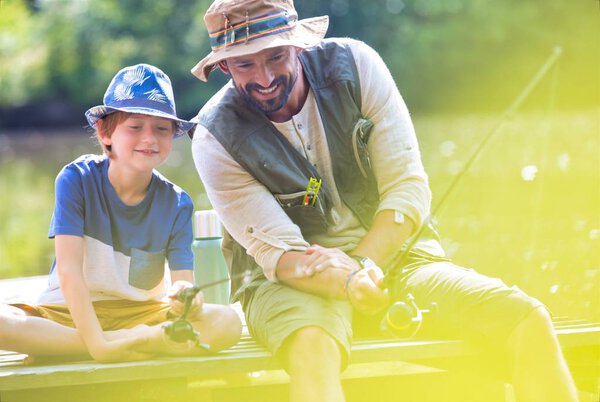 Father and son fishing in Lake while sitting on pier