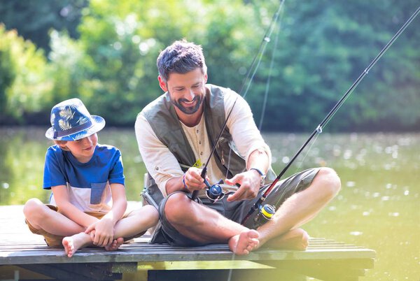 Father and son fishing in Lake while sitting on pier