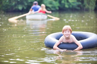 Aile karşı gölde şişme halka ile yüzen gülümseyen çocuk Portresi