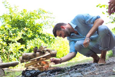 Kamp ateşi için ormanı aydınlatan adam.