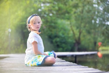 Kız gölün üzerinde iskelede oturuyor.