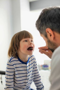 Hastanedeki hastaların bademciklerini kontrol eden doktor.