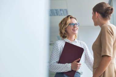 Kendine güvenen iş kadınları yeni ofiste dururken tartışıyorlar