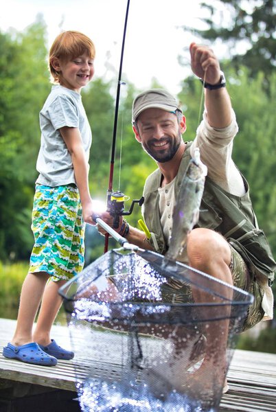 Father and son fishing in Lake while sitting on pier