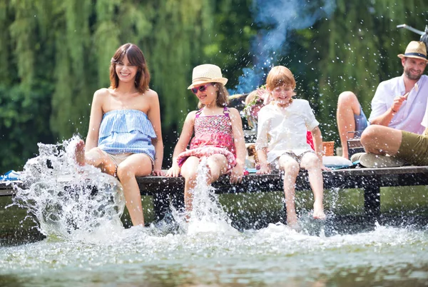 Foto Mãe Jogando Água Com Crianças Lago Enquanto Sentado Cais — Fotografia de Stock