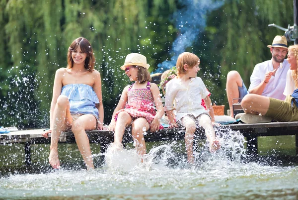 Foto Mãe Jogando Água Com Crianças Lago Enquanto Sentado Cais — Fotografia de Stock