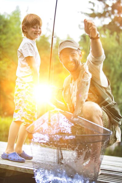 Father and son fishing in Lake while sitting on pier