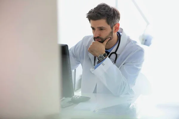 Retrato del médico confiado usando computadora en el escritorio en el hospital —  Fotos de Stock