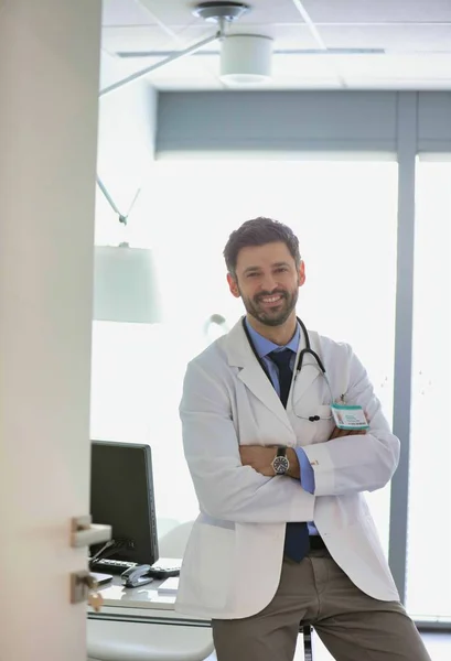 Retrato de un médico de confianza sonriente que utiliza el ordenador en el escritorio en h. —  Fotos de Stock