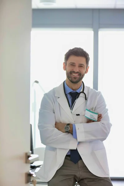 Retrato de un médico de confianza sonriente que utiliza el ordenador en el escritorio en h. —  Fotos de Stock