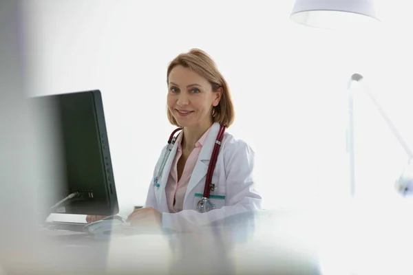 Retrato del médico sentado en el escritorio de la computadora en el hospital —  Fotos de Stock