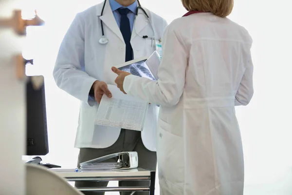 Médicos discutiendo sobre registros médicos en el escritorio en el hospital —  Fotos de Stock