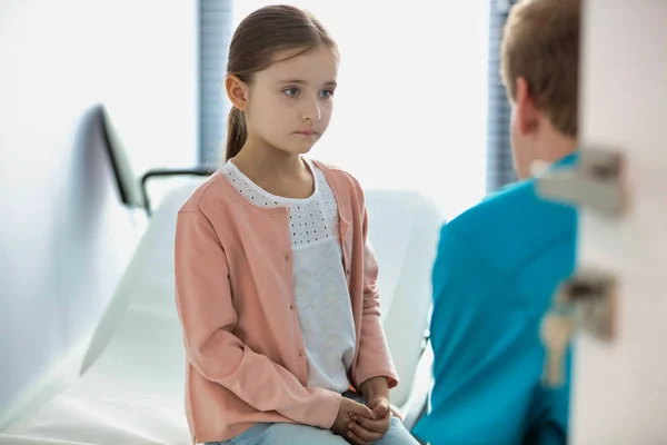 Nurse talking to girl sitting at hospital — Stock Photo, Image