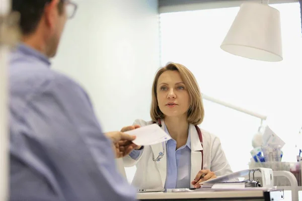 Лікар дає рецепт пацієнту за столом у лікарні — стокове фото