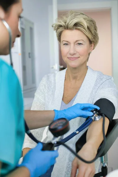 Doctor con guantes que comprueban la presión arterial del paciente en la fosita — Foto de Stock