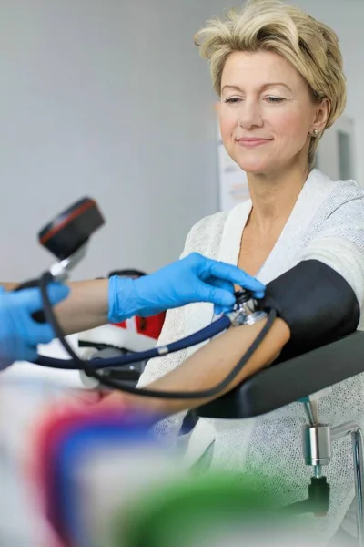 戴手套检查住院病人血压的医生 — 图库照片