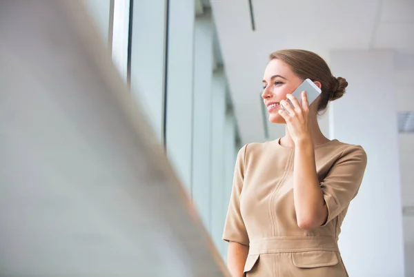 Zakenvrouw aan het praten op smartphone terwijl ze op nieuw kantoor staat — Stockfoto