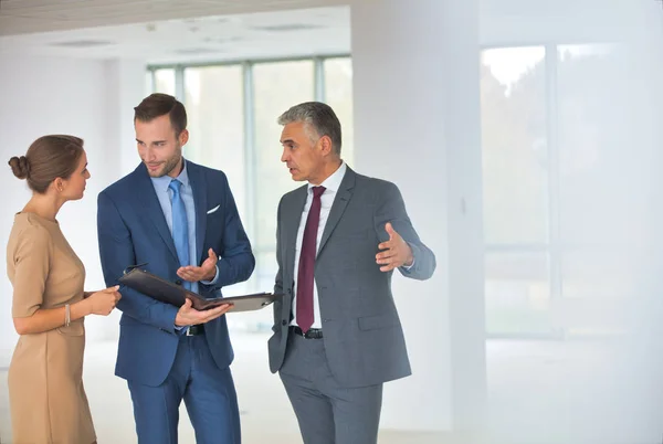 Sorridente uomo d'affari maturo gesticolando ai colleghi al nuovo ufficio — Foto Stock