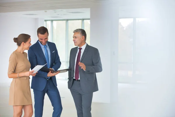 Glimlachende volwassen zakenman gebaren naar collega 's op nieuw kantoor — Stockfoto