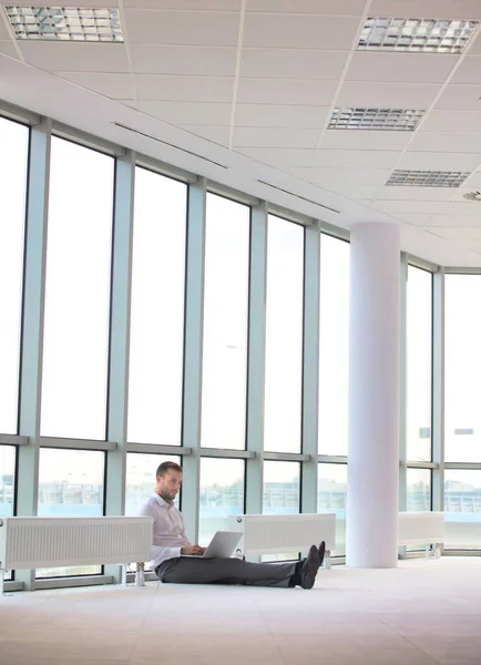 Junger Geschäftsmann Sitzt Mit Laptop Zwischen Heizkörpern Gegen Fenster Büro — Stockfoto