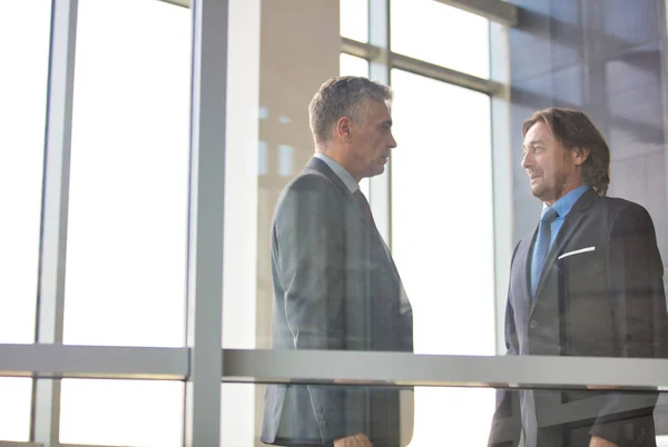 Mature businessmen discussing over document seen through glass i — Stock Photo, Image