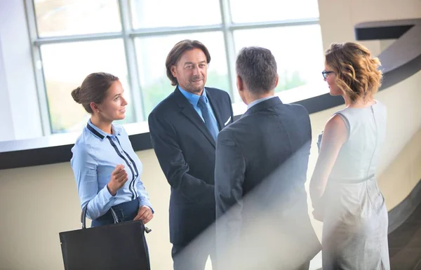 レセプションで同僚と一緒に立ちながら挨拶をするビジネスマン — ストック写真