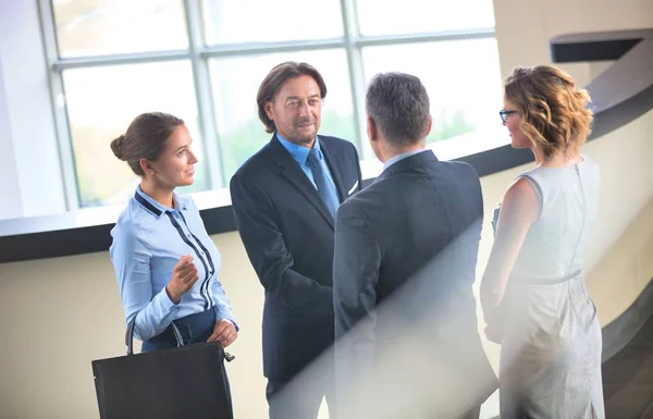 Zakenmensen begroeten elkaar terwijl ze bij de receptie met collega 's staan — Stockfoto