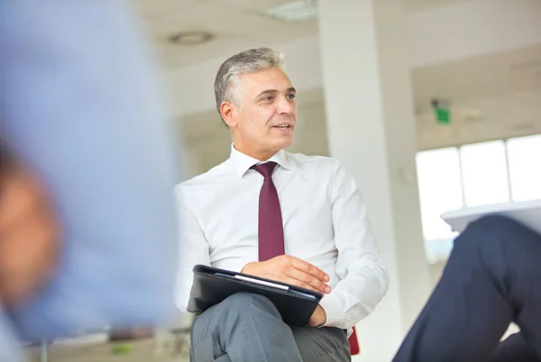 Volwassen zakenman kijken naar collega 's terwijl zitten tijdens mij — Stockfoto