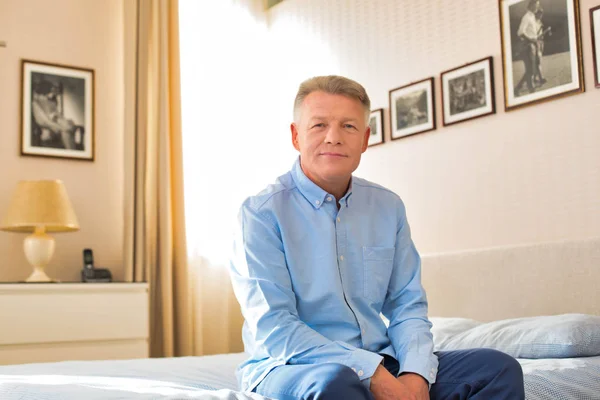 Portrét dospělého muže sedícího doma na posteli — Stock fotografie