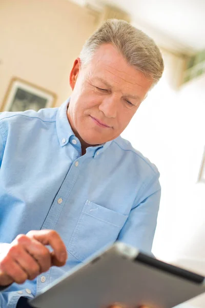Зрелый человек с помощью цифрового планшета дома — стоковое фото