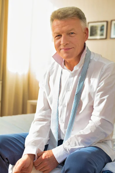 Portrait of confident businessman buttoning sleeve while sitting — Stock Photo, Image