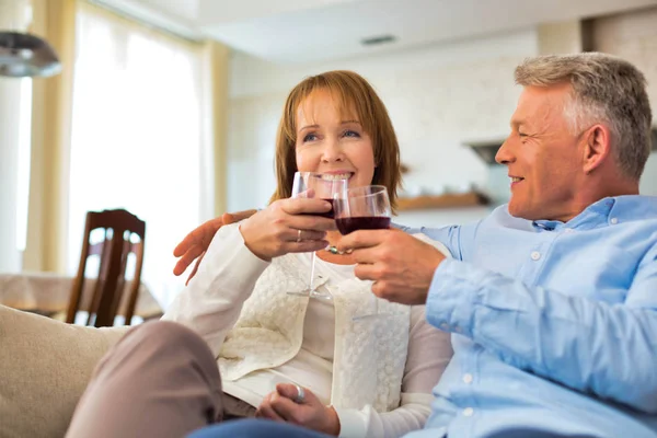 Smiling Mature Couple Sitting Sofa While Holding Drinks Home — Stock Photo, Image