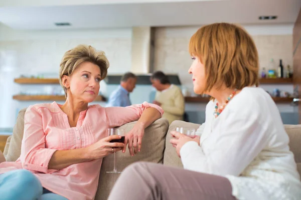 Mature women drinking wine while sitting in sofa at home — Stock Photo, Image