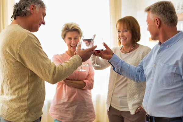 Улыбающиеся взрослые друзья, стоящие с напитками дома — стоковое фото