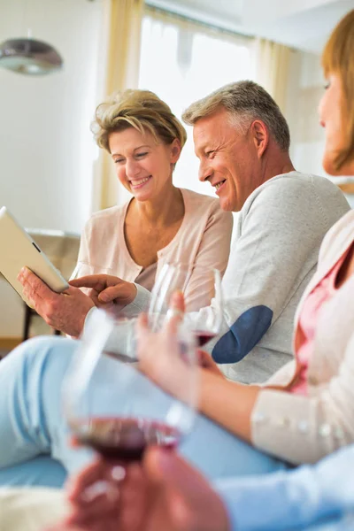 Man showing digital tablet to friend while sitting at home — Stock Photo, Image