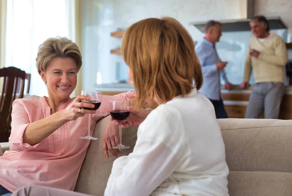 Donne mature brindare mentre si siede sul divano a casa — Foto Stock