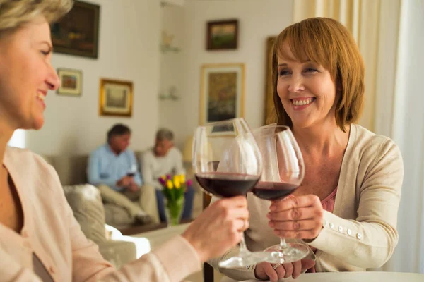 Leende kvinnor som håller drinkar medan de sitter vid matbordet — Stockfoto