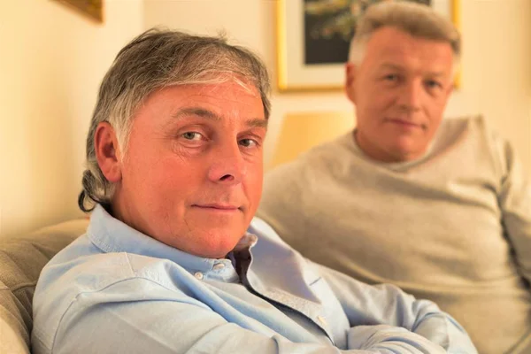 Portrait of smiling mature men sitting on sofa at home — Stock Photo, Image