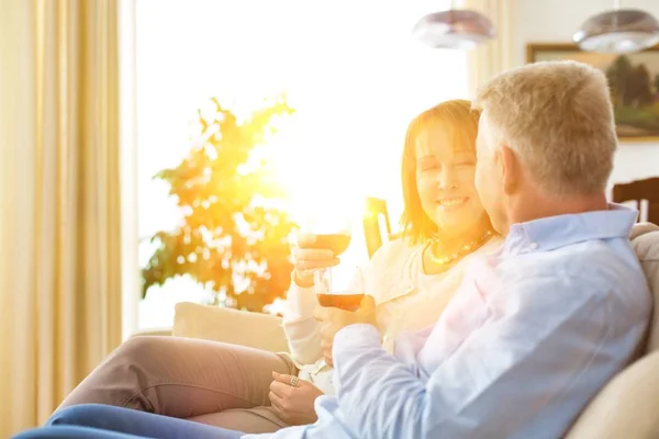 Leende Mogna Par Sitter Soffan Medan Håller Drinkar Hemma — Stockfoto