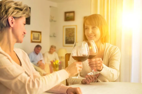 Seniors drinking wine at a party at their home