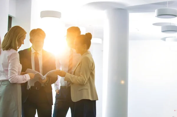 Business group meeting in the office with a strong yellow lens flare in the background