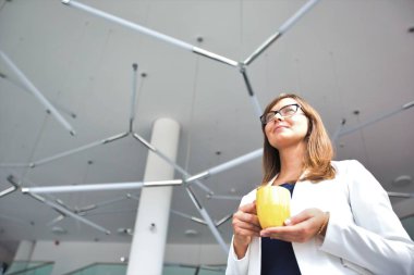 Ofiste dururken kahve bardağı tutan iş kadınının düşük açılı görünümü