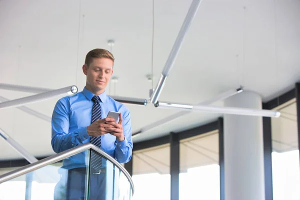 Hombre Negocios Sonriente Usando Teléfono Inteligente Mientras Está Pie Oficina — Foto de Stock