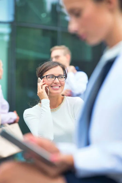 Geschäftsfrau Spricht Auf Smartphone Während Sie Gegen Bürogebäude Sitzt — Stockfoto