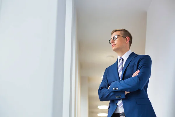 Young Thoughtful Businessman Standing Arms Crossed Looking Away Office Corridor — Stock Photo, Image