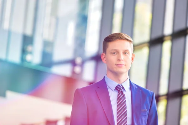 Young blonde male executive in suit looking at the camera