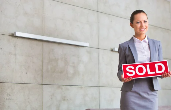 Portrait Confident Young Saleswoman Holding Sold Placard While Standing Wall — Stock Photo, Image